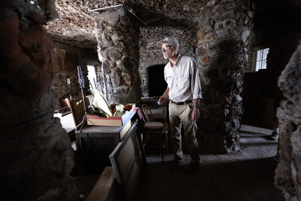 Reed Weimer shines a light on the Indian Cafe inside the World's Wonder Tower Thursday, Aug. 14, 2025, outside Genoa, Colo. The cafe fed travelers at the roadside attraction in the early days through the 1930s.  (The Gazette, Christian Murdock)