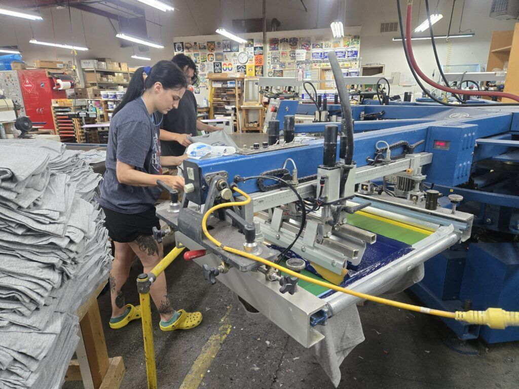 Shirt Stop employees screen print an order of customized T-shirts on one of the presses onsite at Shirt Stop in Colorado Springs.